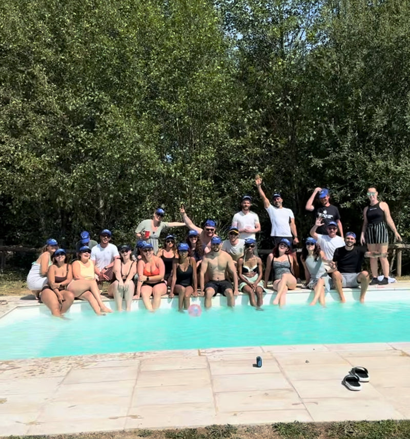 Groupe de participants en casquettes assis au bord de la piscine de la villa