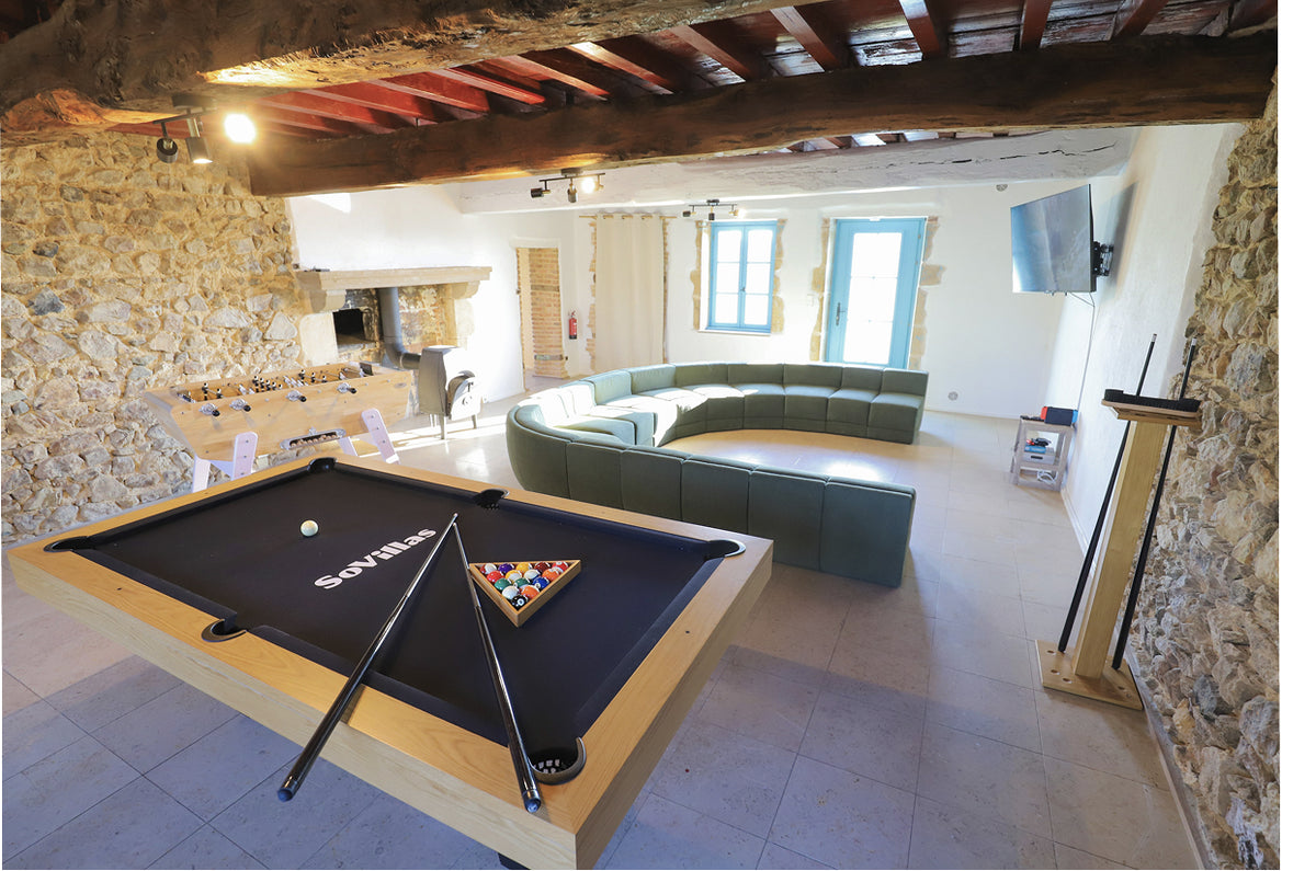 Salle de jeux de la villa avec billard, babyfoot et grand canapé d'angle sous les poutres